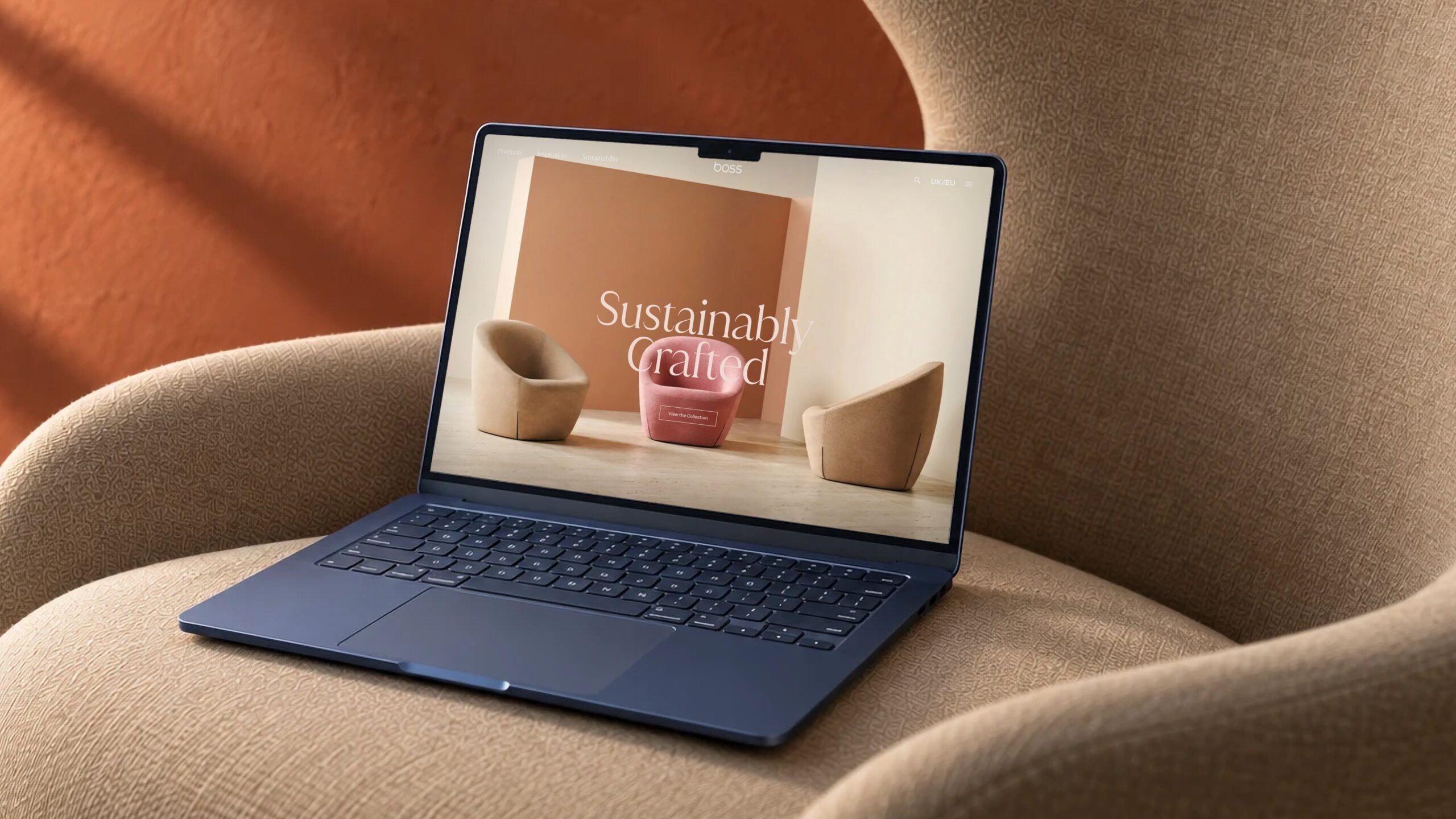 Boss Design website design on a laptop resting on a boucle armchair