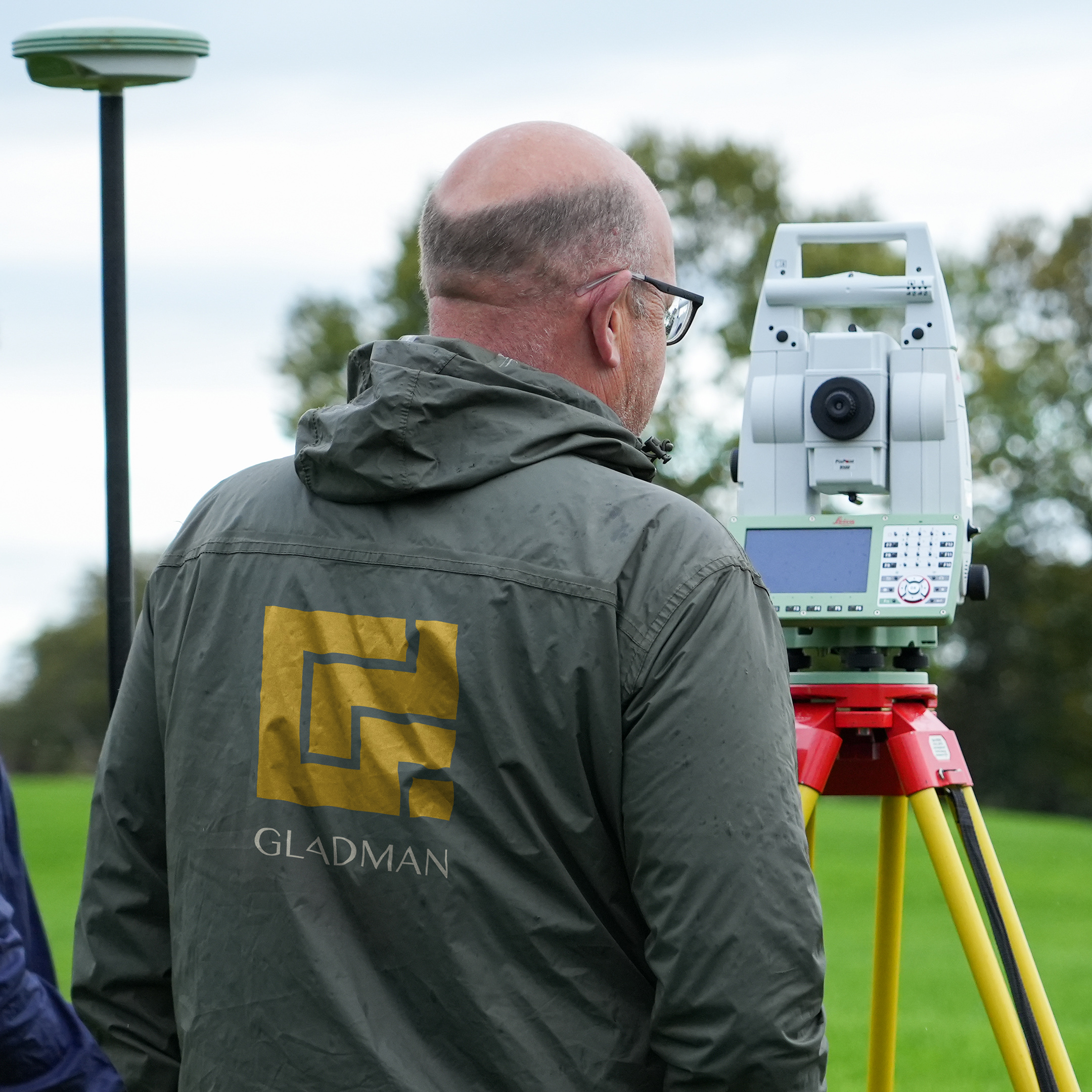 Gladman logo printed on the back of a surveyor's jacket in the field