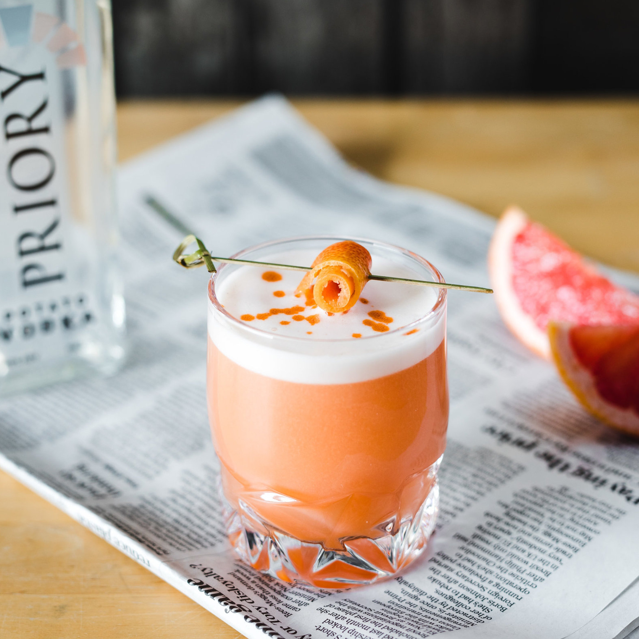 Grapefruit cocktail beside a Priory Vodka bottle on newspaper