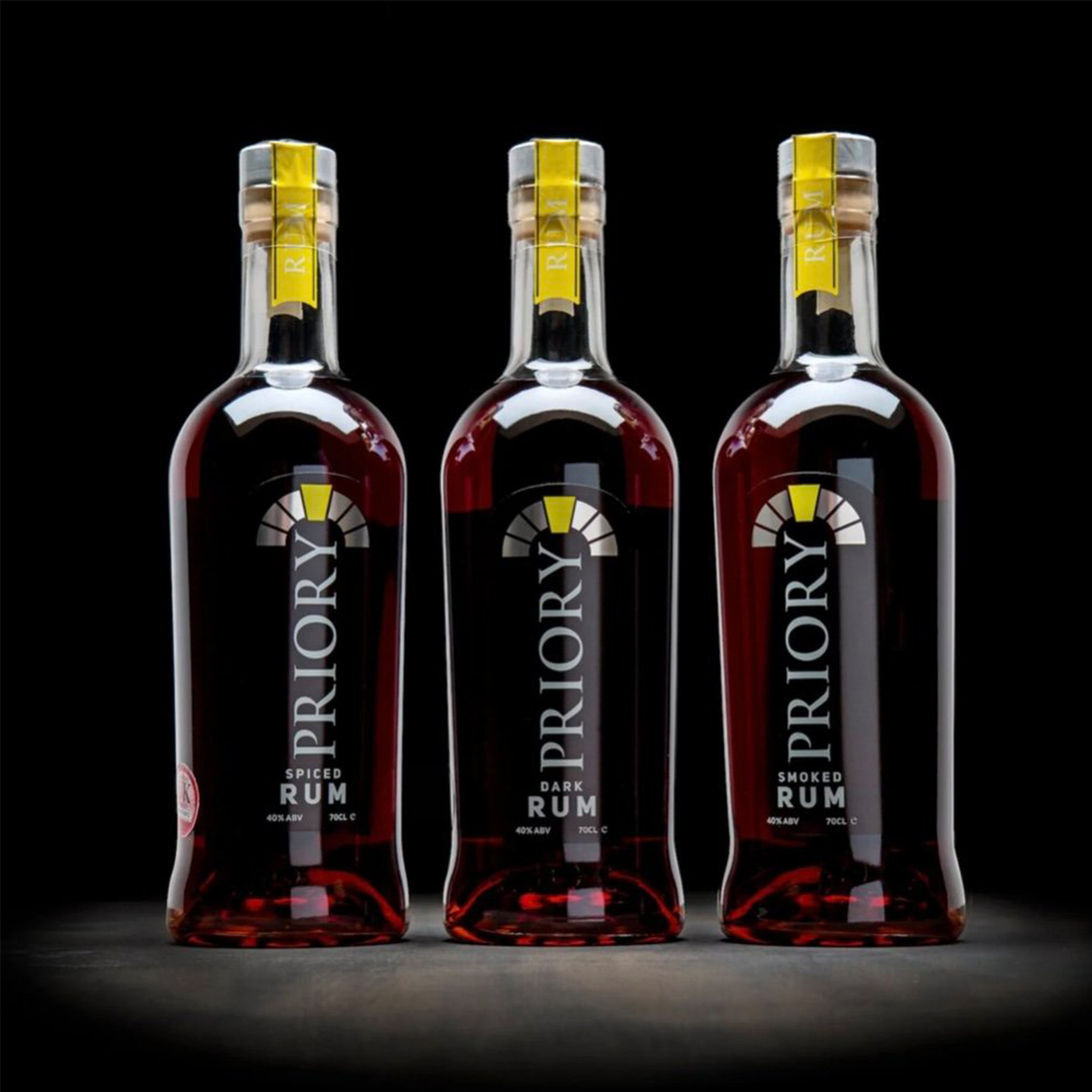 Three bottles of Priory Spiced Rum on black